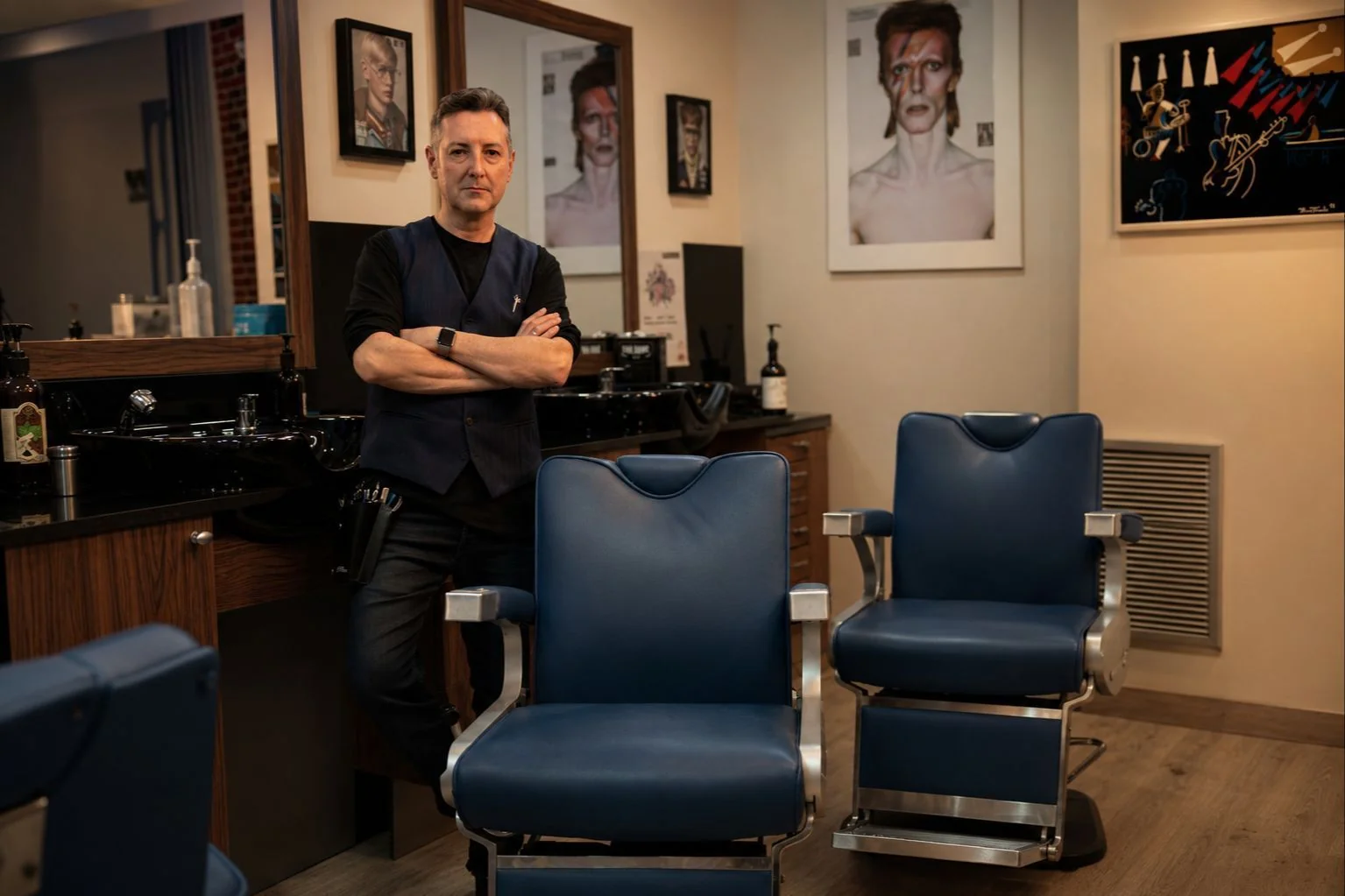Arturo Comín junto a los sillones azules de su peluquería en Zaragoza